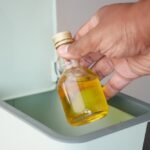 Throwing,Cooking,Oil,Bottle,In,A,Garbage,Bin