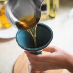 Woman,Pouring,Used,Cooking,Oil,Into,Bottle,Through,Funnel,In