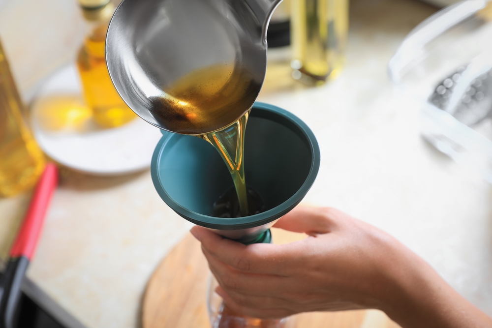 Woman,Pouring,Used,Cooking,Oil,Into,Bottle,Through,Funnel,In